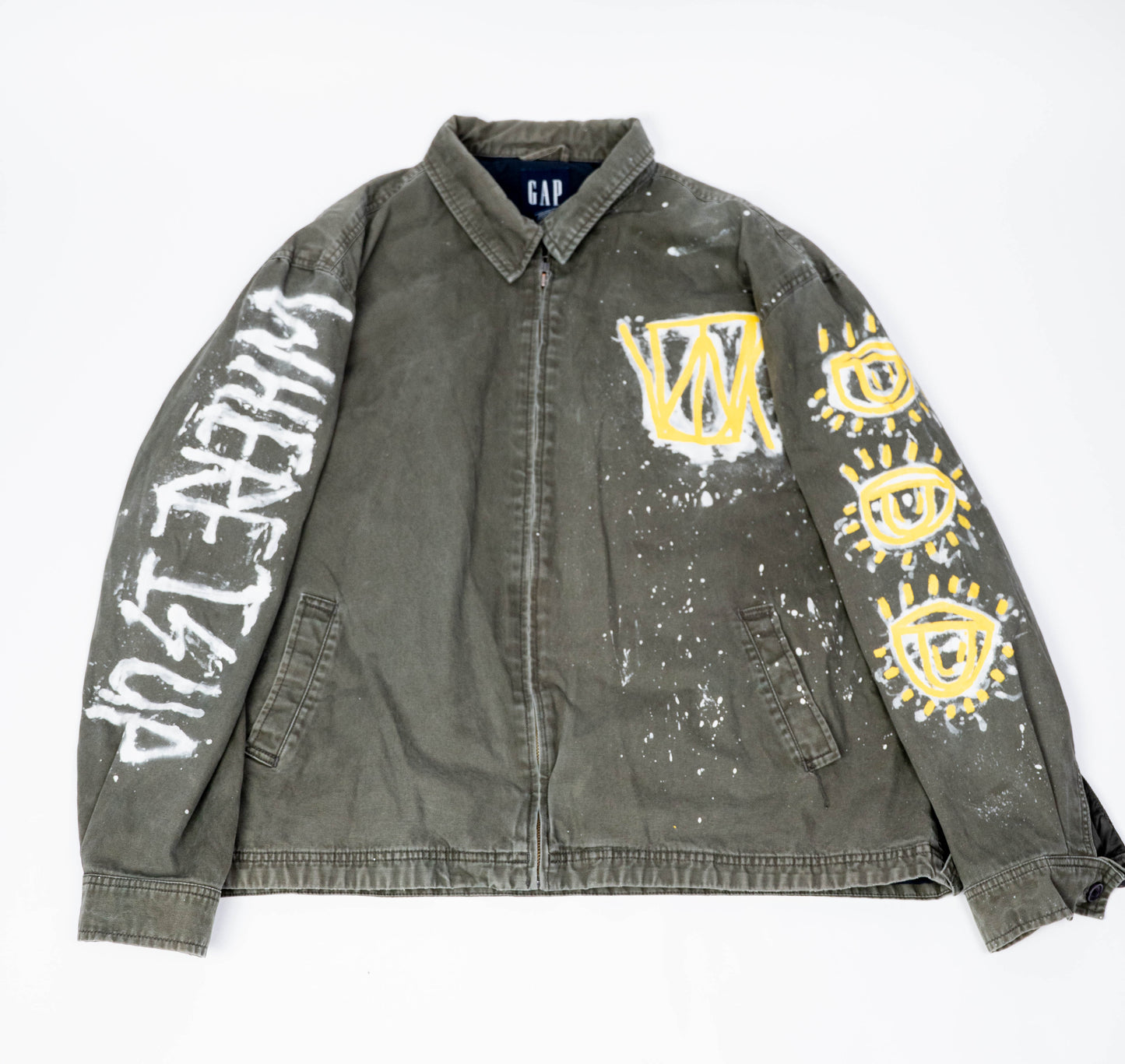 Gray/green canvas jacket with graffiti-style designs on a white background