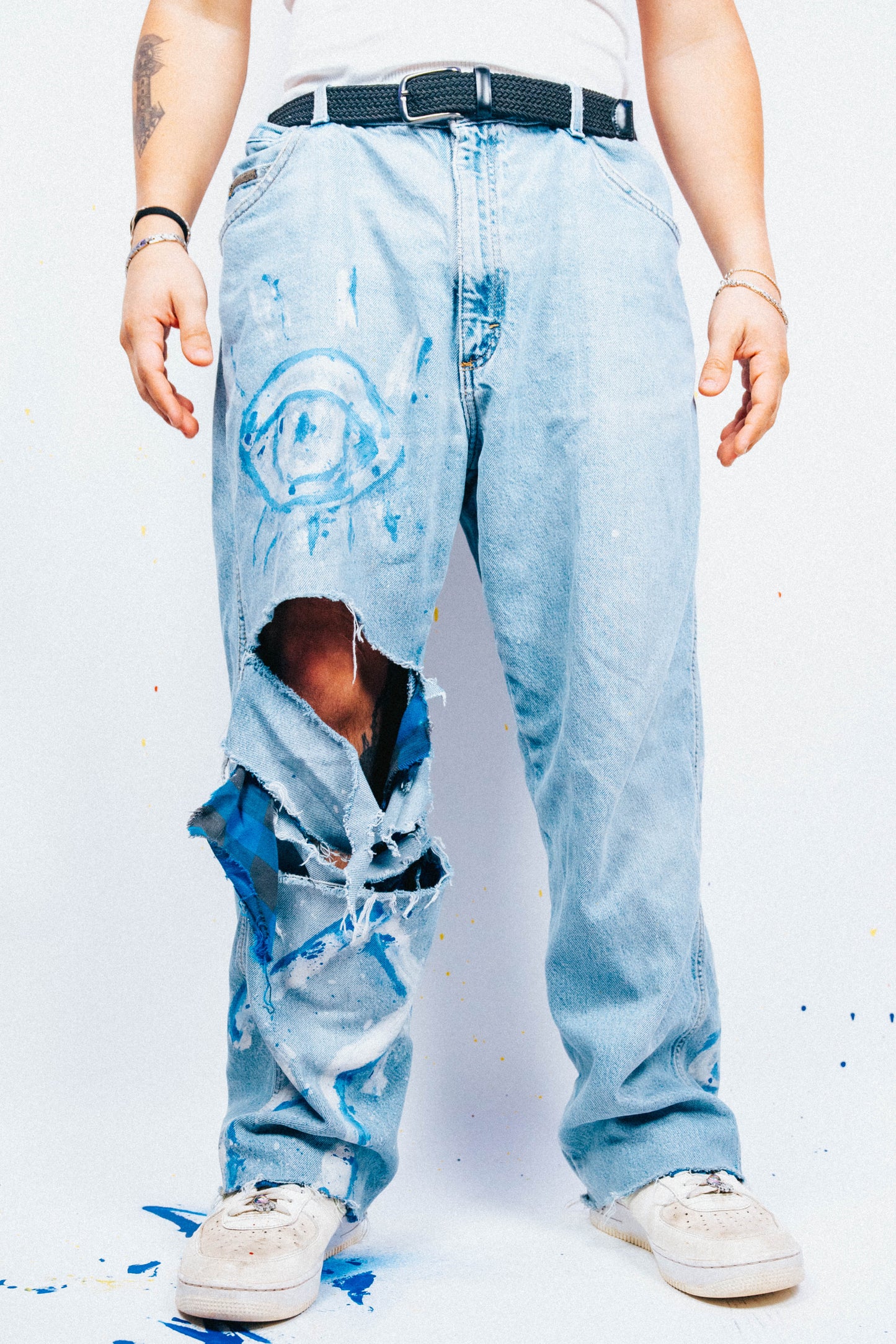 Person wearing light blue 1 of 1 Spray painted ripped jeans on a white background