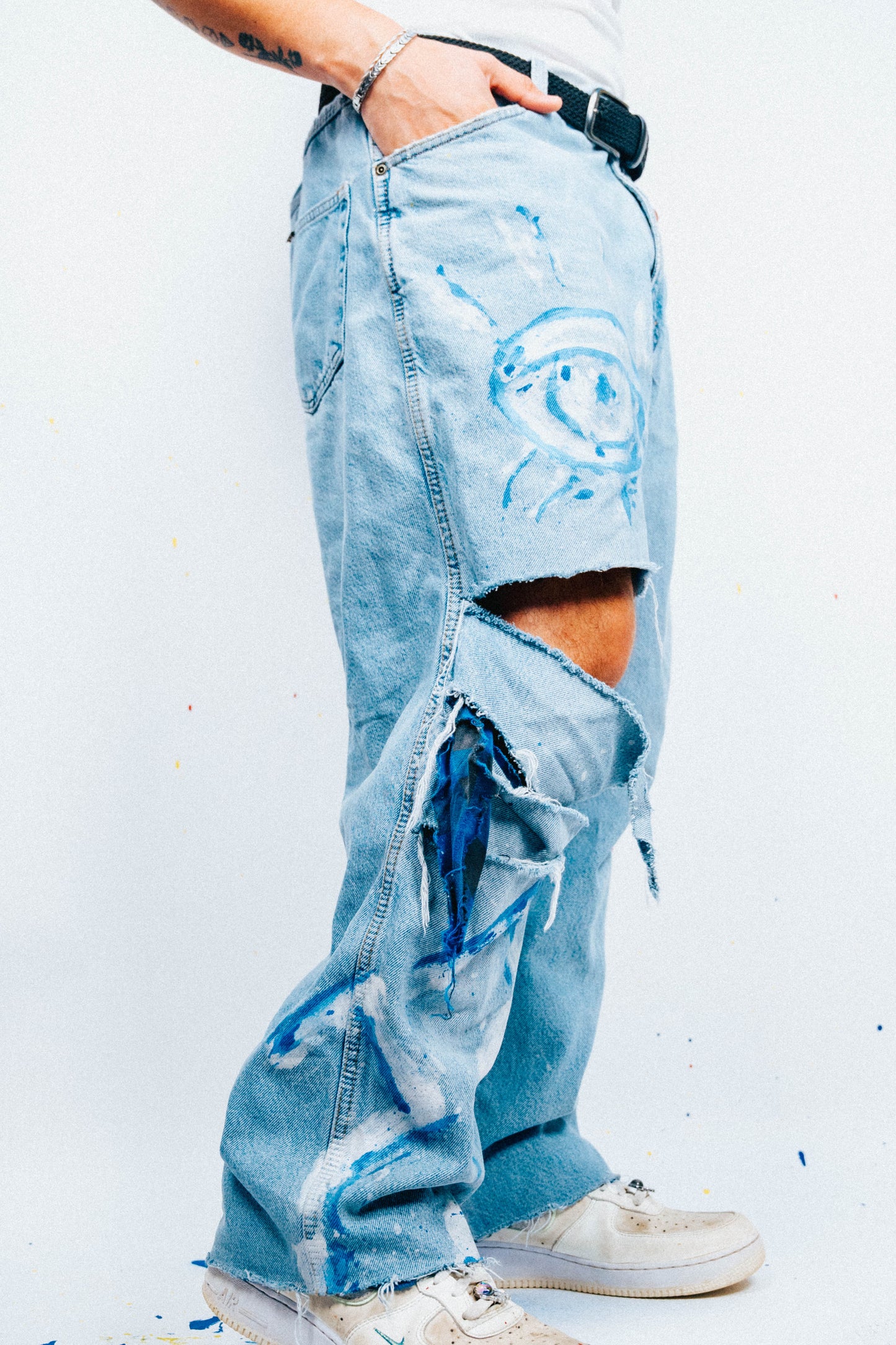 Person wearing light blue 1 of 1 Spray painted ripped jeans on a white background
