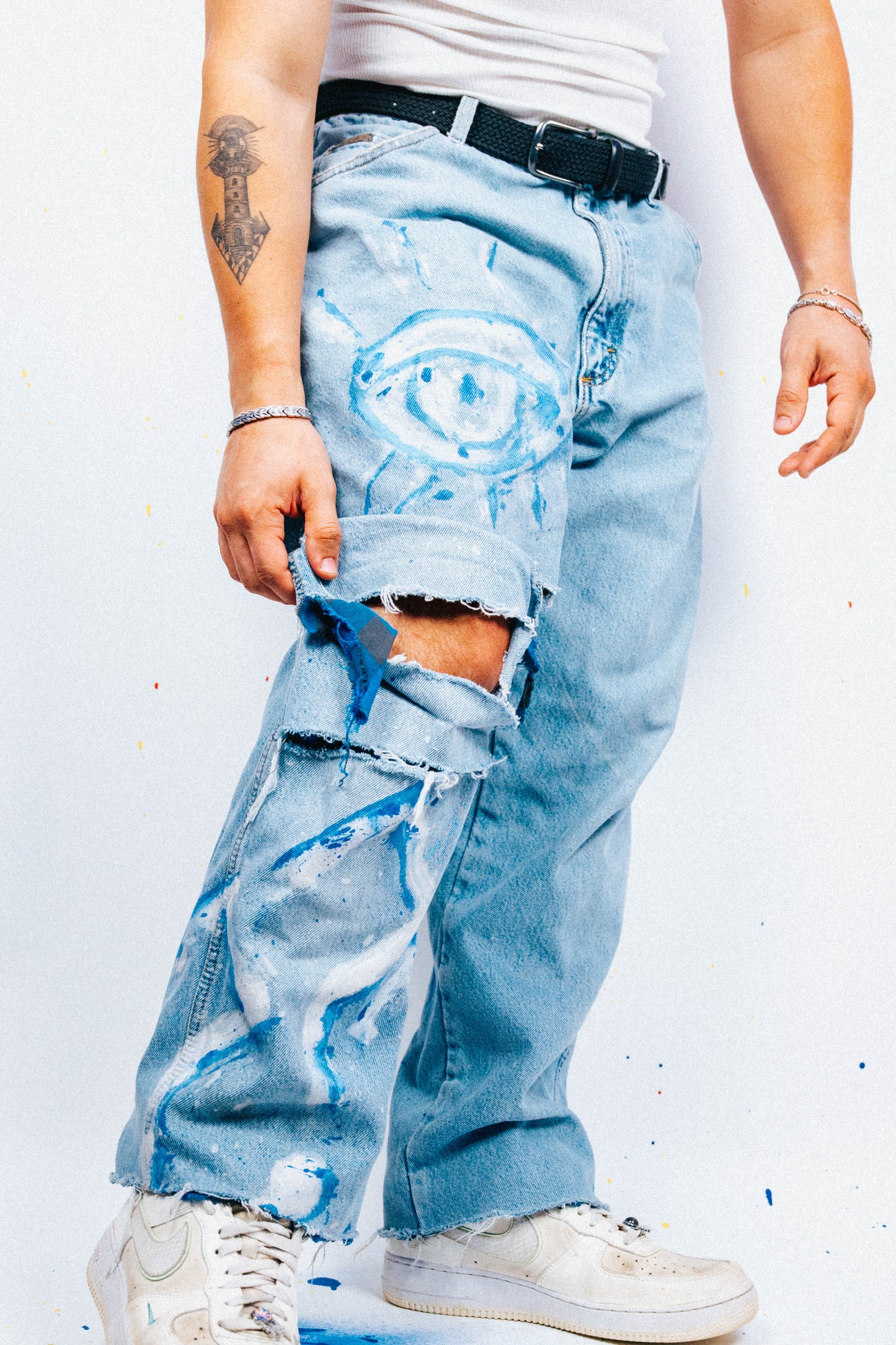 Person wearing light blue jeans with 1 of 1 hand painted graphics on a white background