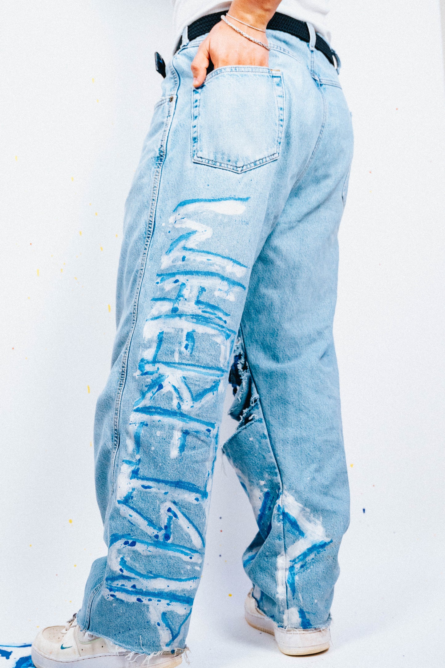 Light blue 1 of 1 spray painted and distressed jeans worn by a person on a white background
