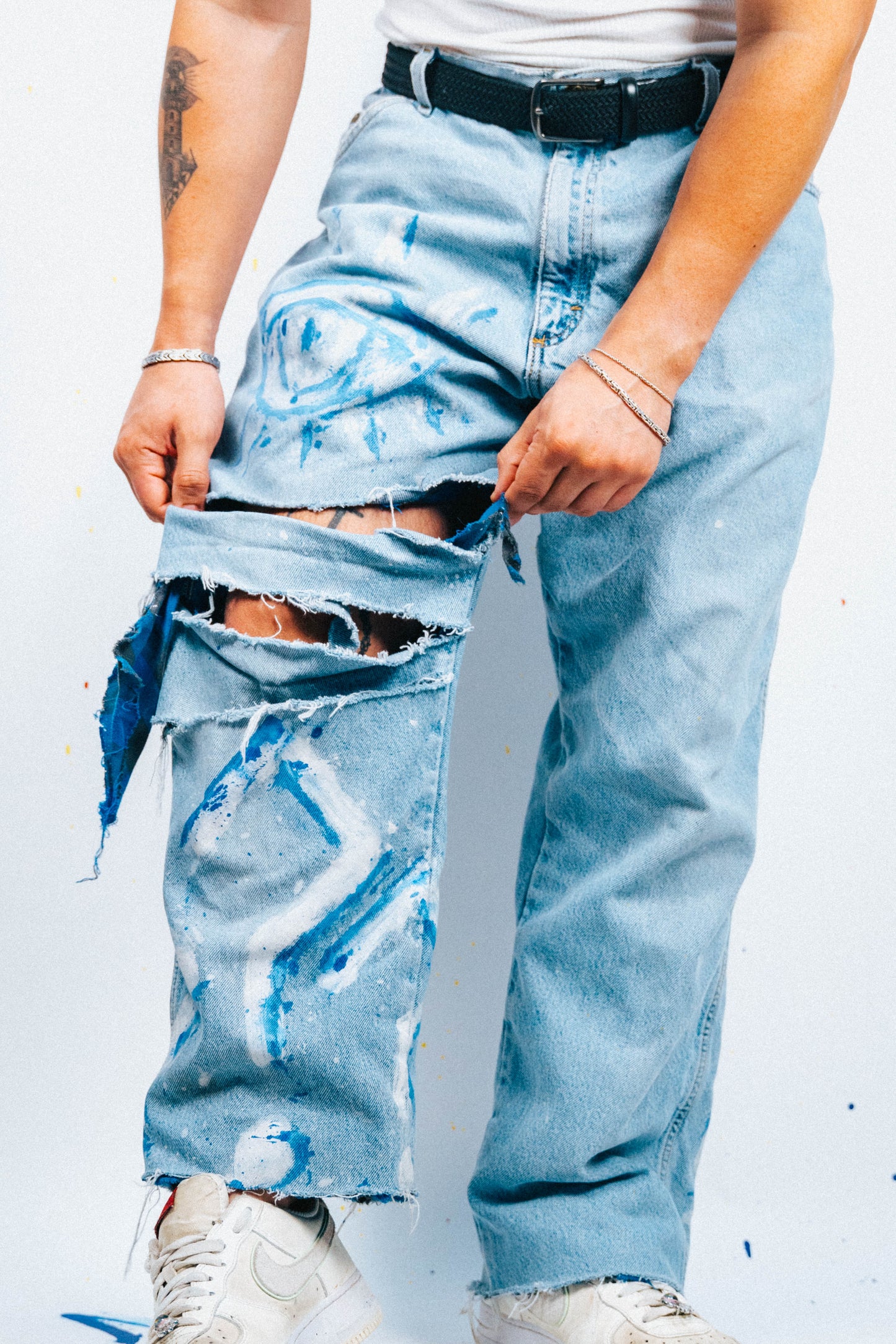 Person wearing light blue 1 of 1 Spray painted ripped jeans on a white background