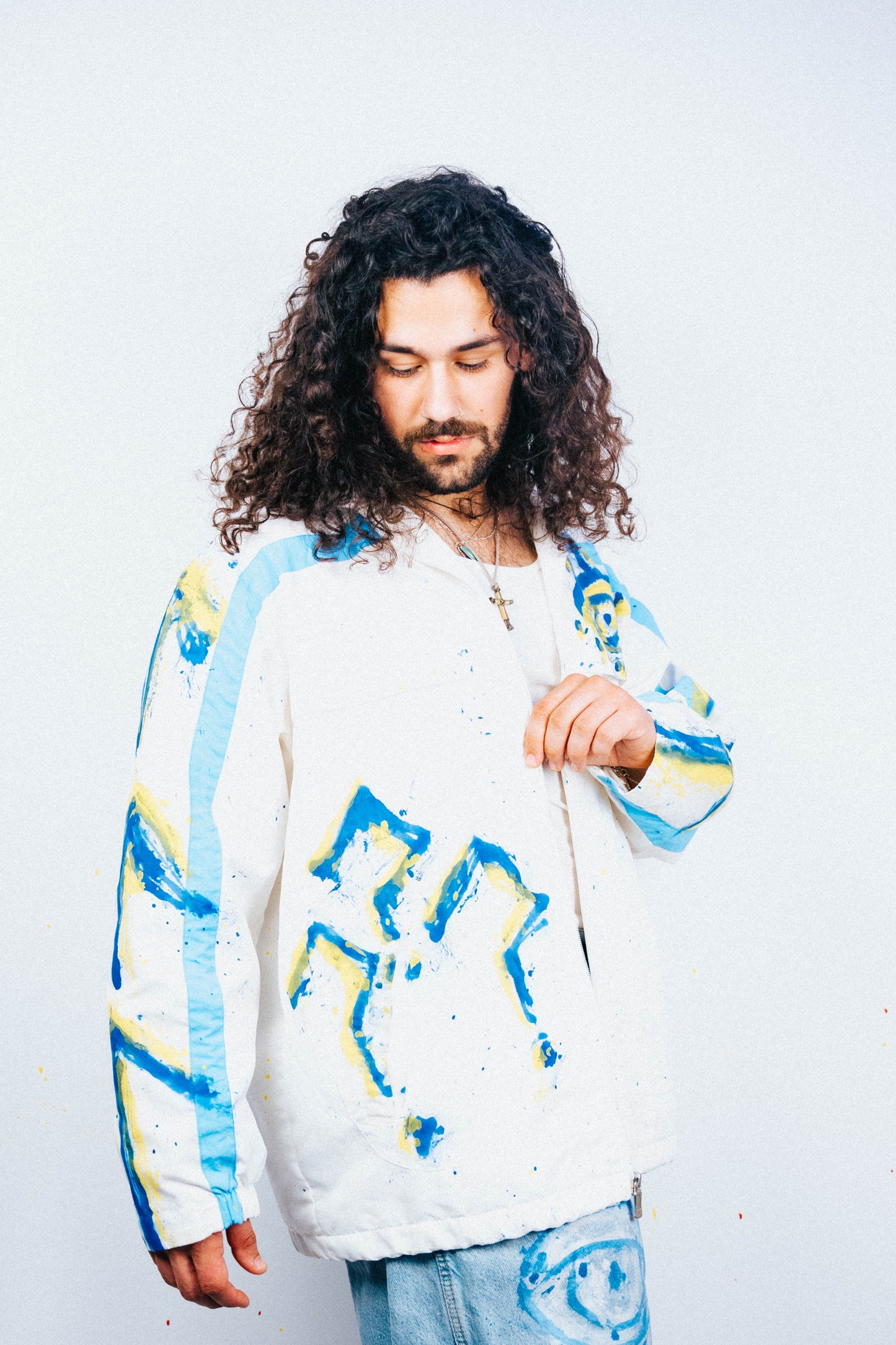 Person wearing a colorful spray painted jacket with abstract designs on a plain background