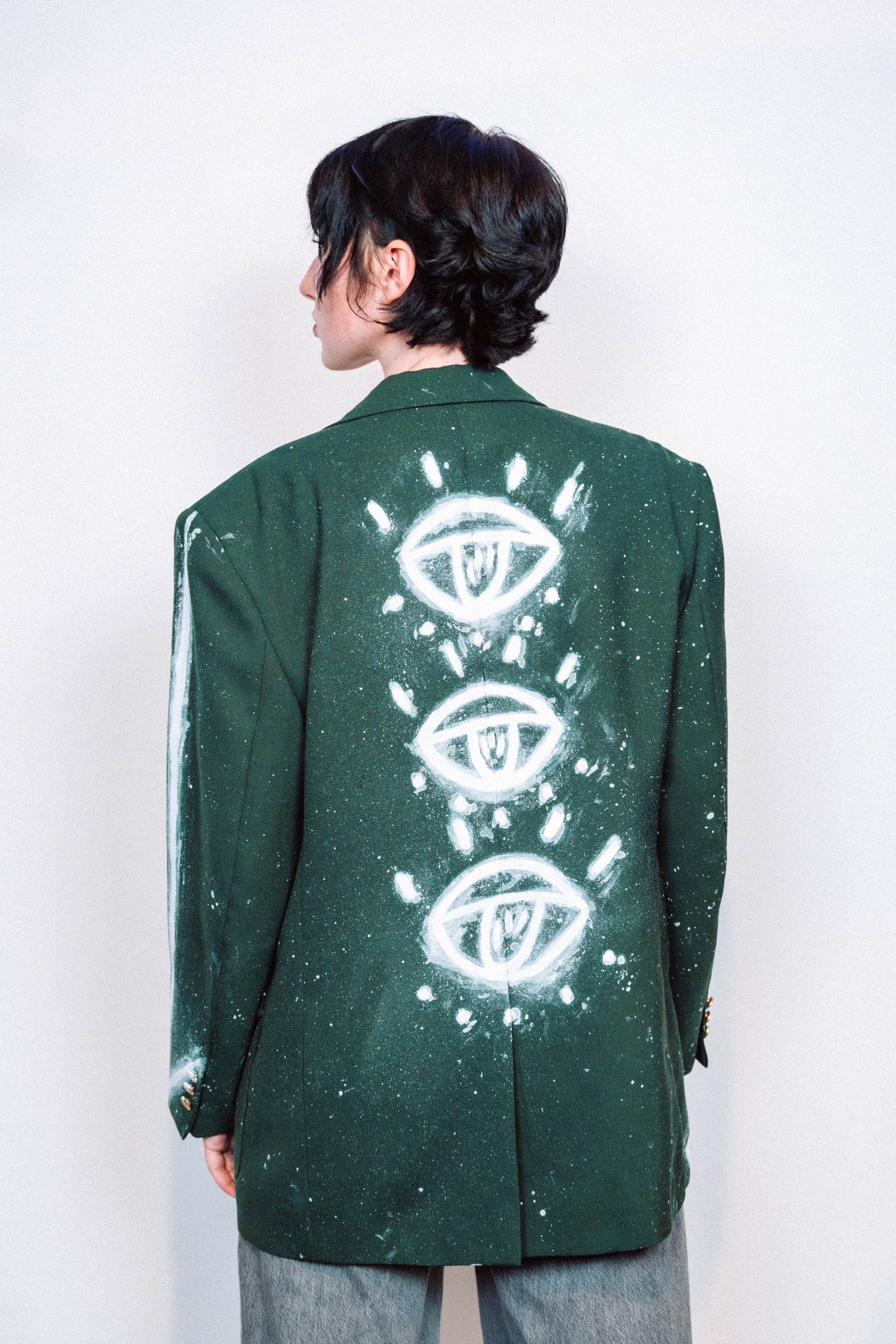 Woman wearing a 1 of 1 Hand Painted and spray painted vintage green suit blazer in front of a white background.