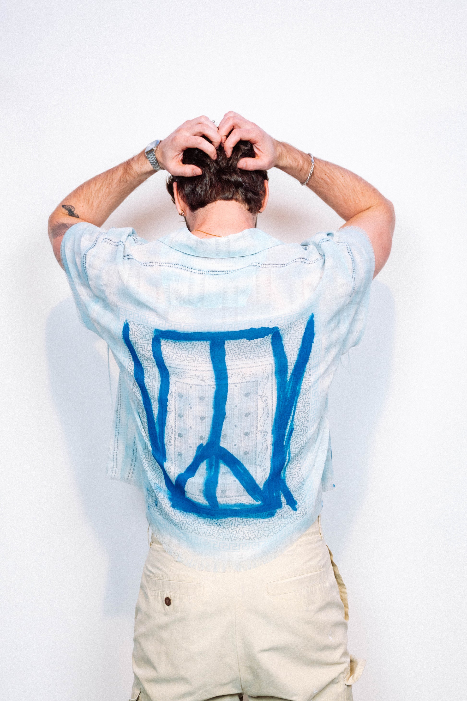 Person wearing a light blue 1 of 1 spray painted button up from "where is up" with blue patterns on a white background