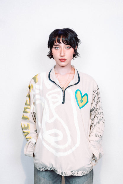 Person Wearing a creme colored 1 of 1 hand painted quarter zip from the brand Where Is Up?