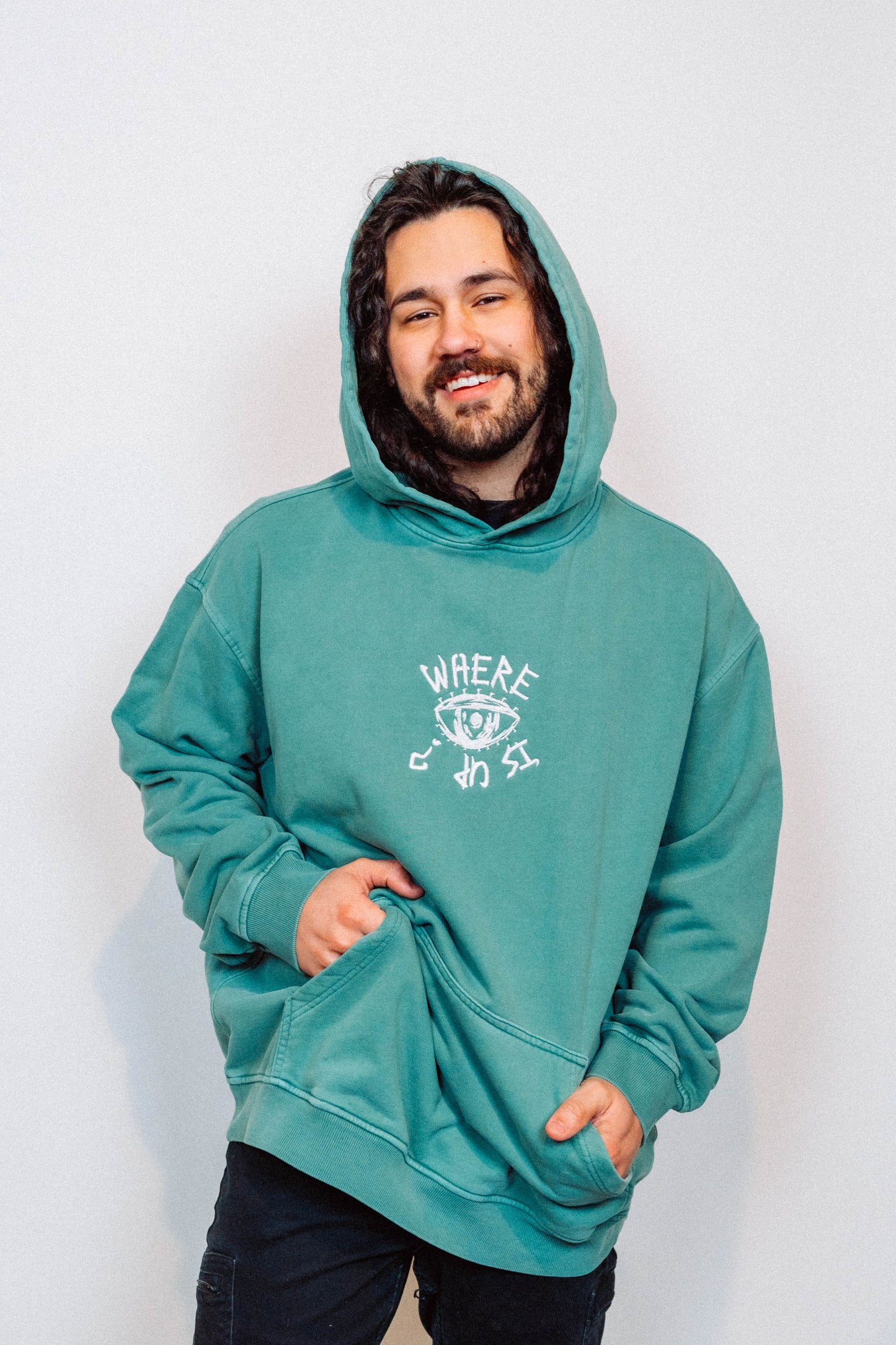 Man wearing a teal hoodie with a logo on a white background