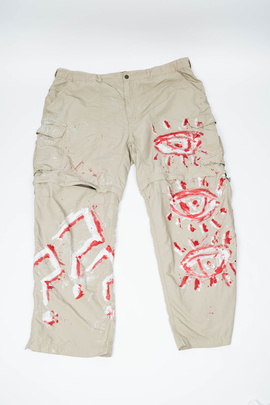 Beige cargo pants with red and white spray painted designs on a white background