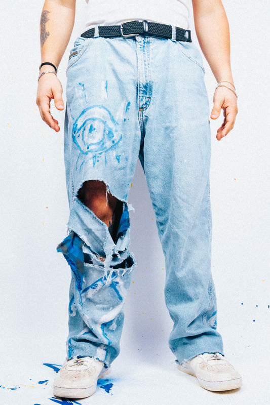 Person wearing light blue 1 of 1 Spray painted ripped jeans on a white background
