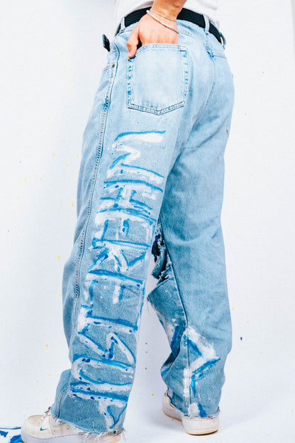 Light blue 1 of 1 spray painted and distressed jeans worn by a person on a white background