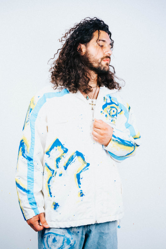 Man wearing a colorful spray painted jacket with abstract patterns on a plain background