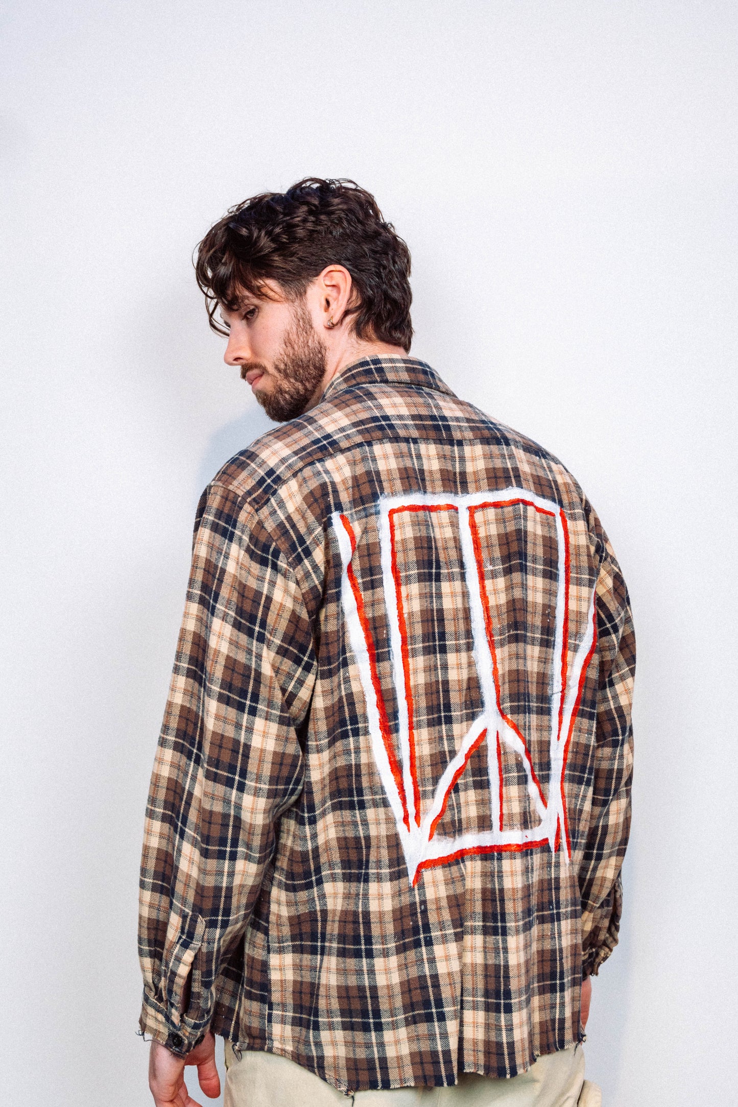 Man wearing a 1 of 1 Hand Painted plaid flannel from luxury wearable art brand "Where Is Up" on a plain background 