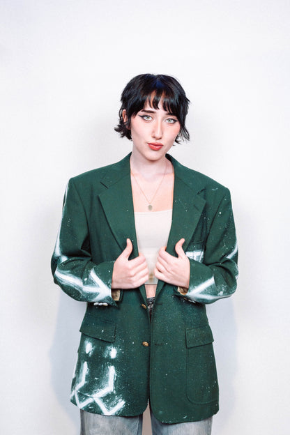 Woman wearing a 1 of 1 Hand Painted and spray painted vintage green suit blazer in front of a white background.