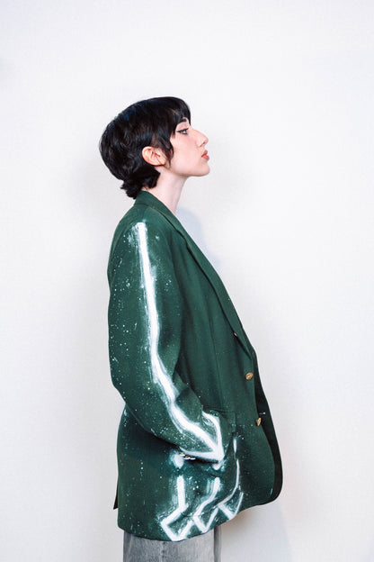 Woman wearing a 1 of 1 Hand Painted and spray painted vintage green suit blazer in front of a white background.